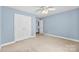 A bright bedroom with light blue walls, carpeted floors, a ceiling fan and a large closet at 6300 Latta Springs Cir, Huntersville, NC 28078