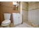 Bathroom featuring a vanity, toilet, and tiled shower with decorative border at 923 Yuma St, Charlotte, NC 28213