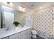 A well-lit bathroom with a double sink vanity, decorative mirror, and a shower with patterned curtains at 10112 Andres Duany Dr, Huntersville, NC 28078