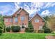 Traditional brick home featuring a well-manicured lawn, lush greenery, and classic architectural details at 103 Samuel Guilford Ct, Charlotte, NC 28270