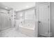 Bright bathroom showcasing a soaking tub, a walk-in shower, and elegant marble flooring at 114 Nevis Ln, Mooresville, NC 28115