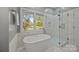 Elegant bathroom featuring a freestanding tub, glass-enclosed shower, and bright window view at 11909 Cupworth Ct, Huntersville, NC 28078