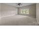 Spacious carpeted bedroom featuring a ceiling fan, neutral color palette, and natural light from the window at 11909 Cupworth Ct, Huntersville, NC 28078