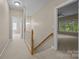 Carpeted hallway with wood railing staircase and access to multiple rooms with natural lighting at 11909 Cupworth Ct, Huntersville, NC 28078