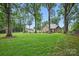 Large backyard with mature trees surrounding a brick home featuring a pool and patio area for entertaining at 12900 Westmoreland Rd, Huntersville, NC 28078
