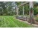 A beautiful backyard featuring a unique bench swing and lush landscaping and mature trees at 12900 Westmoreland Rd, Huntersville, NC 28078