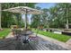 Backyard patio featuring a table and chairs set under an umbrella, with a pool and lounge chairs in the background at 12900 Westmoreland Rd, Huntersville, NC 28078