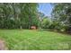 Large backyard with mature trees, a storage shed, and garden beds on a well maintained lawn at 12900 Westmoreland Rd, Huntersville, NC 28078