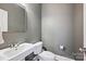 Powder room featuring a white pedestal sink, a toilet, a mirror, and grey paint at 12900 Westmoreland Rd, Huntersville, NC 28078