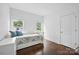 Well-lit bedroom with hardwood floors, white walls, and two windows at 12900 Westmoreland Rd, Huntersville, NC 28078