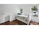 Bright bedroom featuring hardwood floors, white walls, and two windows at 12900 Westmoreland Rd, Huntersville, NC 28078