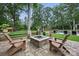 Inviting backyard patio features a stone fire pit, Adirondack chairs, and a serene view of the pool and lush greenery at 12900 Westmoreland Rd, Huntersville, NC 28078