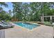 A private pool with a hot tub surrounded by greenery and lounge chairs on a stone patio at 12900 Westmoreland Rd, Huntersville, NC 28078