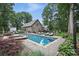 A beautiful home with a pool, lounge chairs, lush landscaping, and mature shade trees in the backyard at 12900 Westmoreland Rd, Huntersville, NC 28078