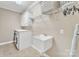 Laundry room with neutral paint, tile floors, utility sink, overhead cabinets and modern washer/dryer at 13056 Long Common Pkwy, Huntersville, NC 28078