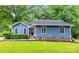 Charming single-story home with a manicured lawn, lush greenery, and a vibrant blue exterior at 13446 Idlefield Ln, Matthews, NC 28105