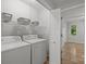 Bright laundry room with washer, dryer, storage shelves, and a bright doorway view at 13446 Idlefield Ln, Matthews, NC 28105