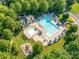 An aerial view showcases a community pool, playground, and clubhouse surrounded by lush greenery at 15001 Rosemary Way Dr, Huntersville, NC 28078