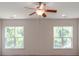 Bright bedroom featuring a ceiling fan and two windows offering views of the outdoor greenery at 15001 Rosemary Way Dr, Huntersville, NC 28078