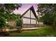 Striking stone home with a wall of windows framed by lush trees against a vibrant sky at 1515 Heatherloch Dr, Gastonia, NC 28054