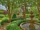 Beautiful backyard with a stone fountain, lush greenery, and manicured trees at 1522 High St, Charlotte, NC 28211