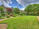 Expansive backyard featuring lush lawn, landscaped gardens, and elegant stone home under a partly cloudy sky at 1522 High St, Charlotte, NC 28211