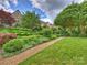 Beautifully landscaped gardens cascading down to a lush green lawn and a luxurious stone home at 1522 High St, Charlotte, NC 28211