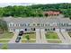 An aerial view displays a row of townhomes with well-manicured lawns, driveways, and green tree line in the distance at 16039 Simril Ct, Charlotte, NC 28278