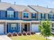 Street view of townhomes featuring manicured lawns, colorful exteriors, and attached garages at 16039 Simril Ct, Charlotte, NC 28278