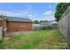 View of backyard featuring a well-maintained lawn, brick home, and wooden fence at 1609 Mcfarland Dr, Shelby, NC 28152