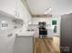 A kitchen is shown with white cabinets, stainless appliances, and wood-look floors at 1908 Harvest Ln # 5, Charlotte, NC 28210