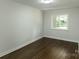 Bright bedroom featuring refinished hardwood floors, fresh paint, and a window with backyard views at 1936 Russell Ave, Charlotte, NC 28216