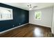 Bedroom features a dark accent wall, hardwood floors, neutral paint, and window overlooking the backyard at 1936 Russell Ave, Charlotte, NC 28216