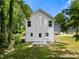 Backyard view of a home with white siding, a small patio, and a grassy area, surrounded by trees at 208 N Correll St, Landis, NC 28025