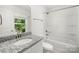 Bright bathroom featuring a granite countertop, modern fixtures, and a shower and tub combo with a window at 208 N Correll St, Landis, NC 28025