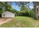 Large, grassy backyard showcasing a detached garage with ample space and potential for various uses, surrounded by mature trees at 2601 Ashley Rd, Charlotte, NC 28208