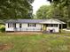 Charming single story home featuring a cozy porch, black shutters, and a bright yellow door at 2903 Price Rushing Rd, Monroe, NC 28110