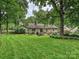 Sprawling backyard featuring a patio, mature trees, and lush green lawn at 2911 Butter Churn Ln, Matthews, NC 28105