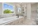 Luxurious bathroom with a freestanding tub, glass-enclosed shower, and marble tile at 3058 Tramore Dr, Harrisburg, NC 28075