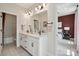 Bathroom featuring double sinks, white cabinets, and a view into the primary bedroom at 3058 Tramore Dr, Harrisburg, NC 28075