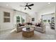 Bright living room with a large sectional sofa, ceiling fan, and views from large windows at 3058 Tramore Dr, Harrisburg, NC 28075