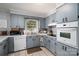 Cozy kitchen featuring blue cabinets, white appliances, and a window with a pleasant view at 3424 Autumn Dr, Gastonia, NC 28056