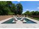 Luxury pool with built in seating, umbrellas, and sunning area surrounded by lush trees and landscape at 4021 Redwood Ave, Charlotte, NC 28205