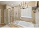 A well-lit bathroom featuring a glass-enclosed shower, a large soaking tub, and decorative accents at 4430 Bravery Sw Pl, Concord, NC 28027