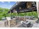 Covered outdoor kitchen features a stainless steel grill, bar seating, and an adjacent jacuzzi at 4430 Bravery Sw Pl, Concord, NC 28027