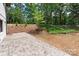 Paver patio in the backyard with mature trees, a grassy area and a small garden, creating a peaceful outdoor retreat at 5033 Waxhaw Indian Trail Rd, Matthews, NC 28104