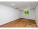 Finished basement room with hardwood floors, white walls, recessed lighting and a window with view of the trees outside at 5033 Waxhaw Indian Trail Rd, Matthews, NC 28104