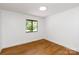 A bedroom featuring hardwood floors, white walls and a window with a view of the outside at 5033 Waxhaw Indian Trail Rd, Matthews, NC 28104