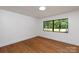Bright bedroom with hardwood floors and natural light streaming through a window with lush green views at 5033 Waxhaw Indian Trail Rd, Matthews, NC 28104