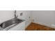 A laundry room featuring a stainless steel sink, white cabinets, and white walls with wooden floors at 5033 Waxhaw Indian Trail Rd, Matthews, NC 28104